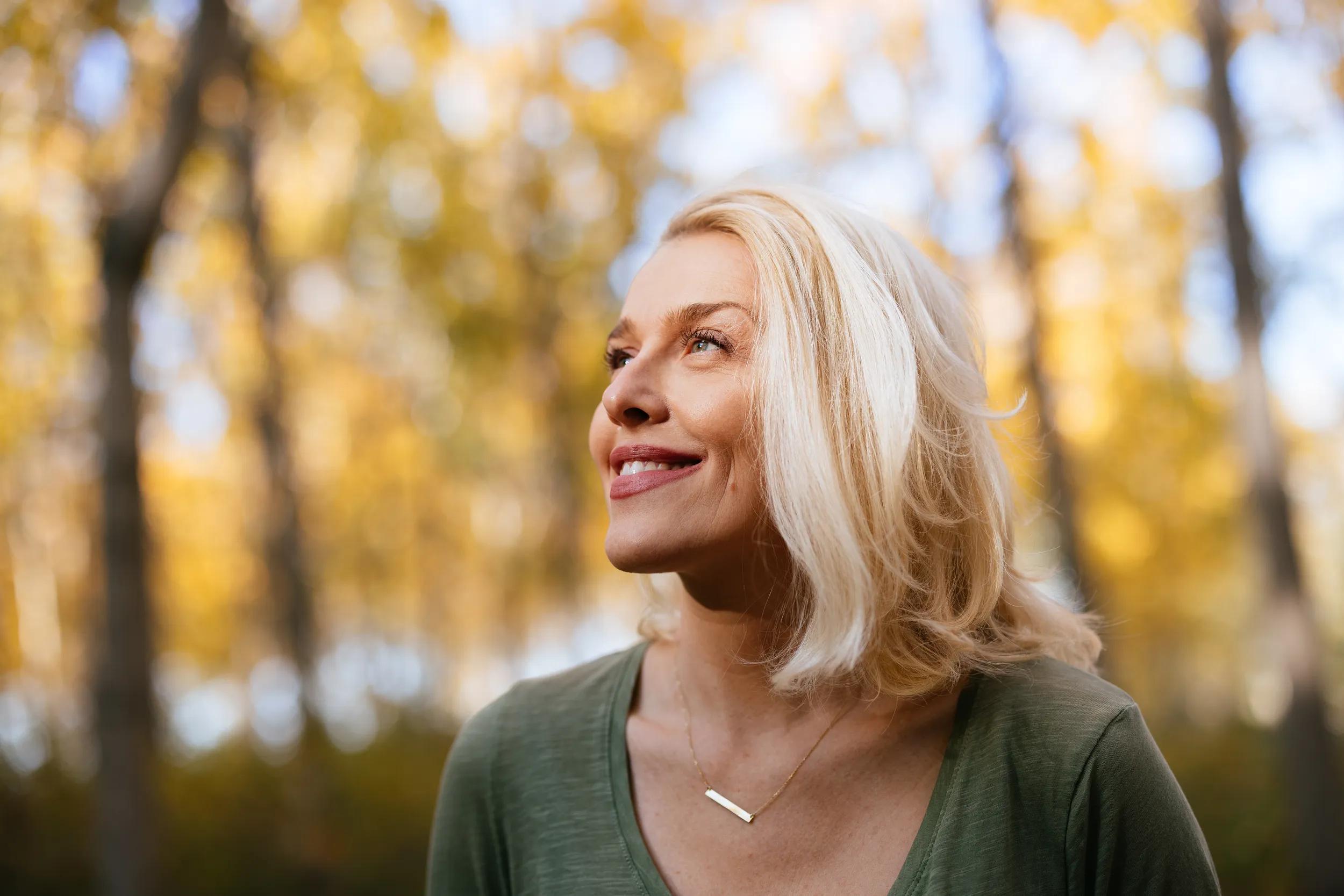 Portrait of a Beautiful Woman Standing in the Woods Enjoying the Sunlight