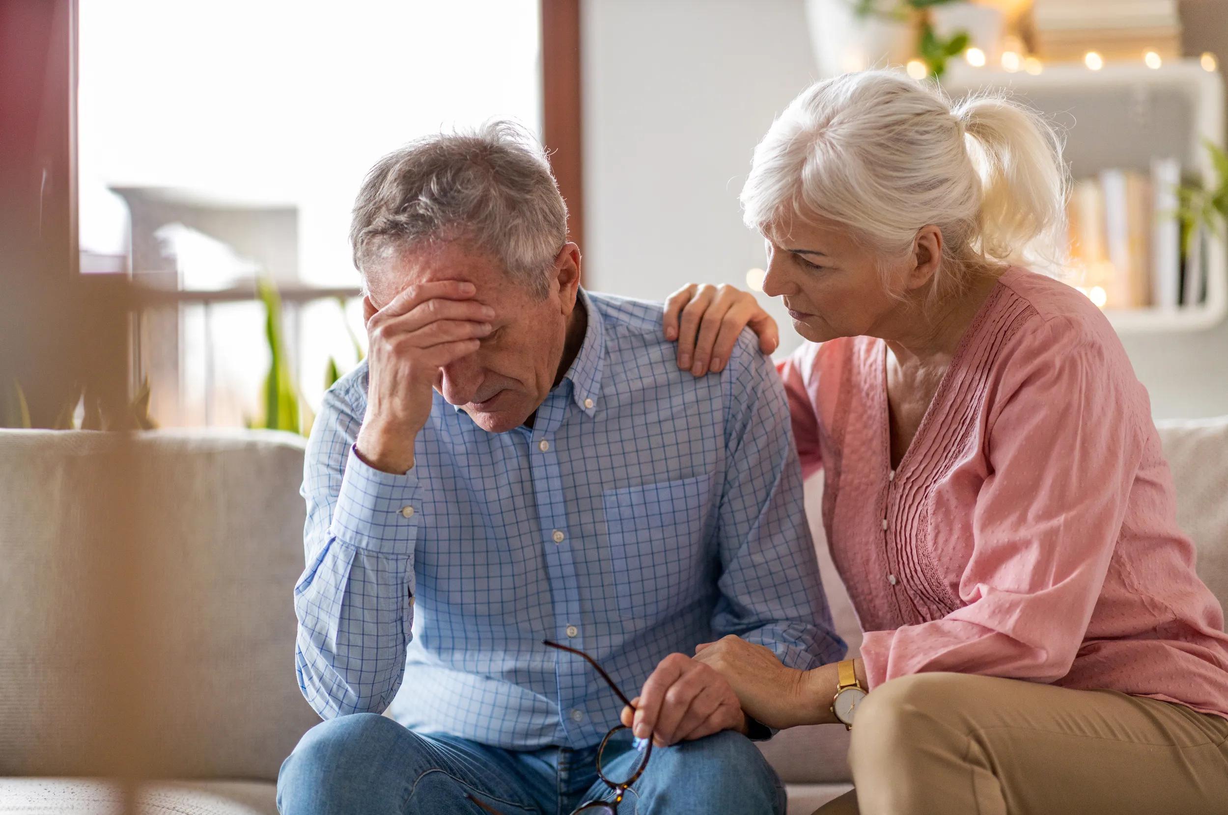 Senior woman consoling her husband at home