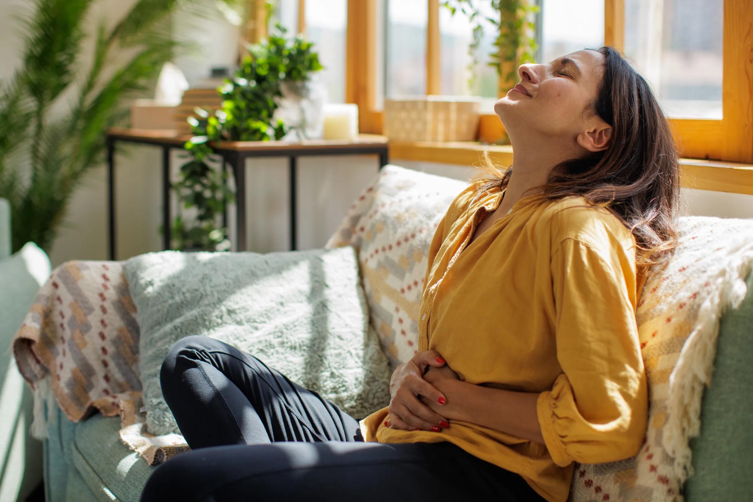 Woman experiencing stomach pain at home