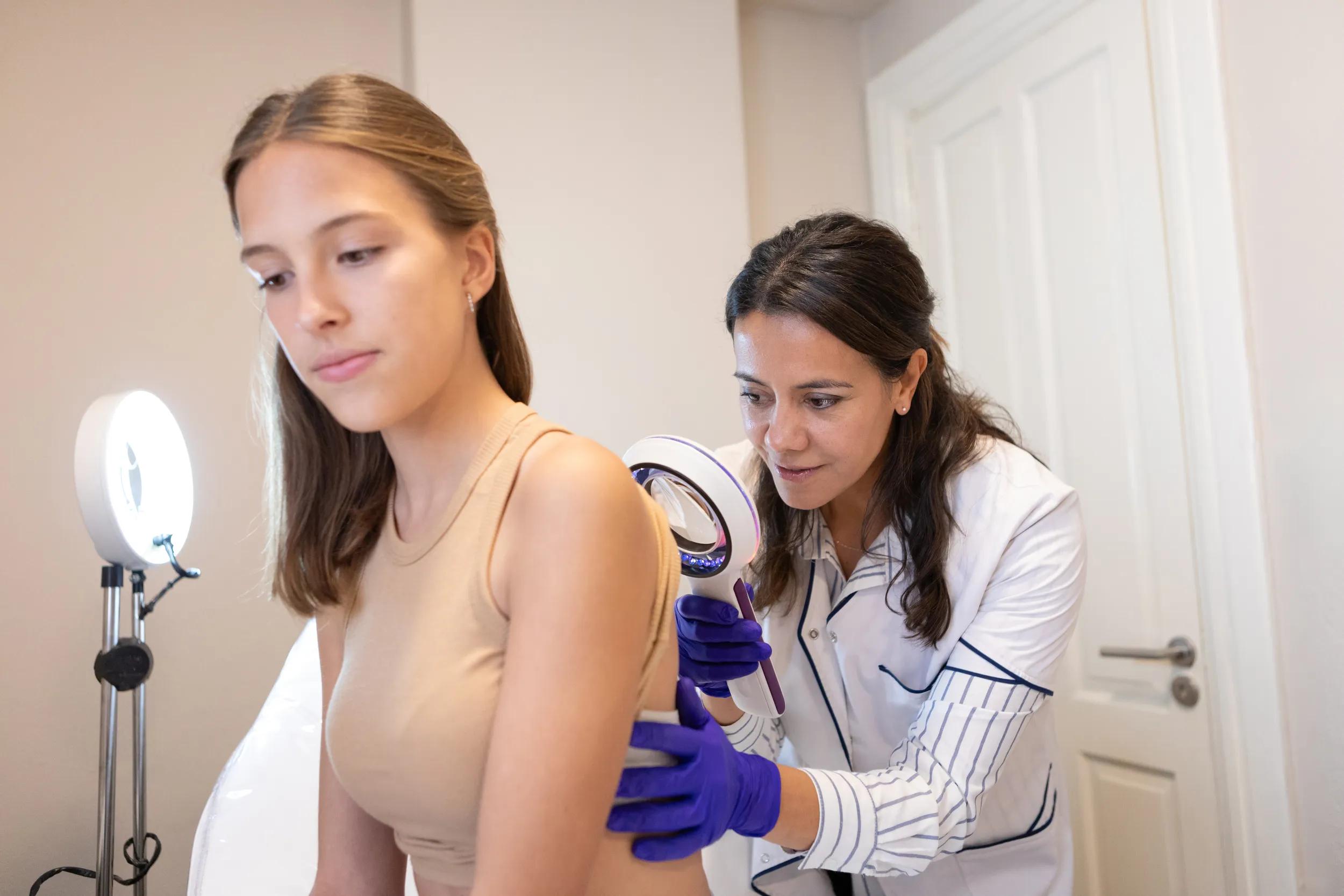 Dermatologist examining her patient with a dermatological magnifying glass