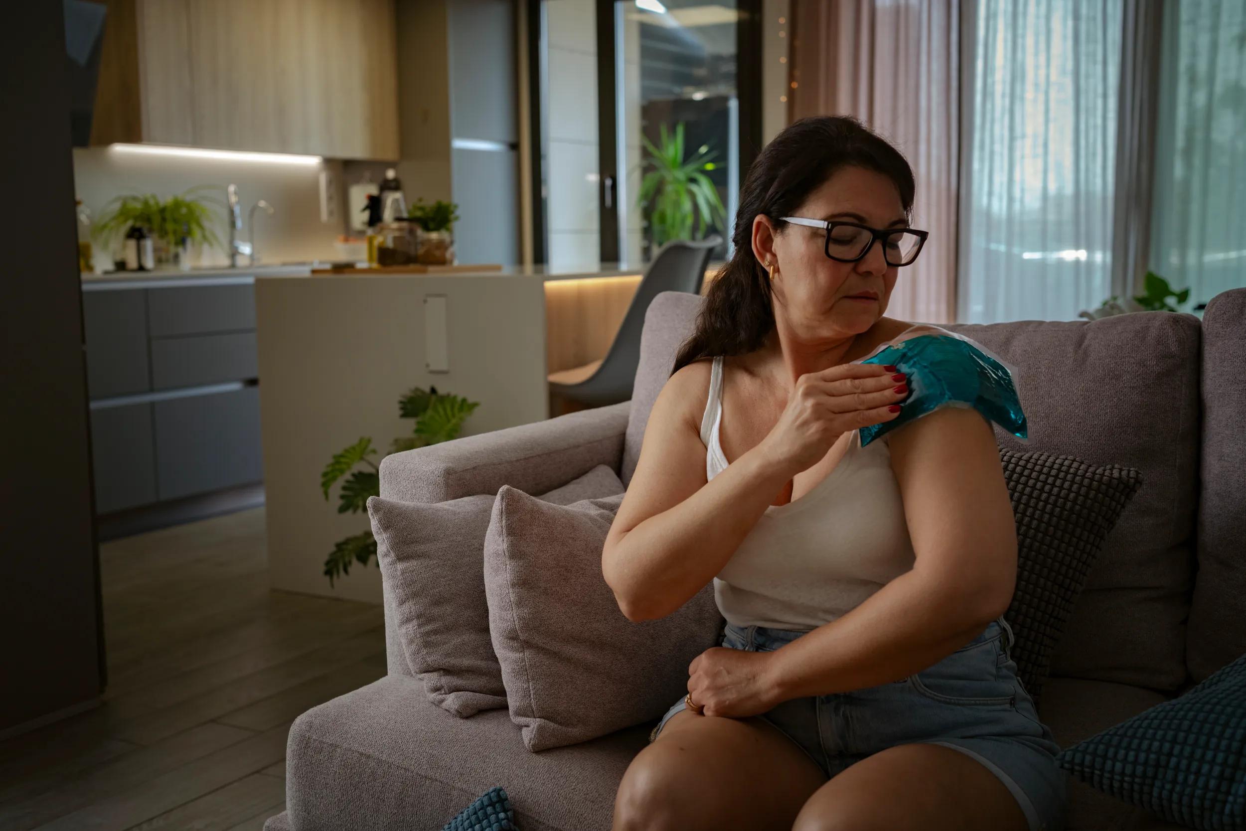 Mature woman applying gel pack on her painful shoulder, ligament, muscle or bone problems. Joint inflammation