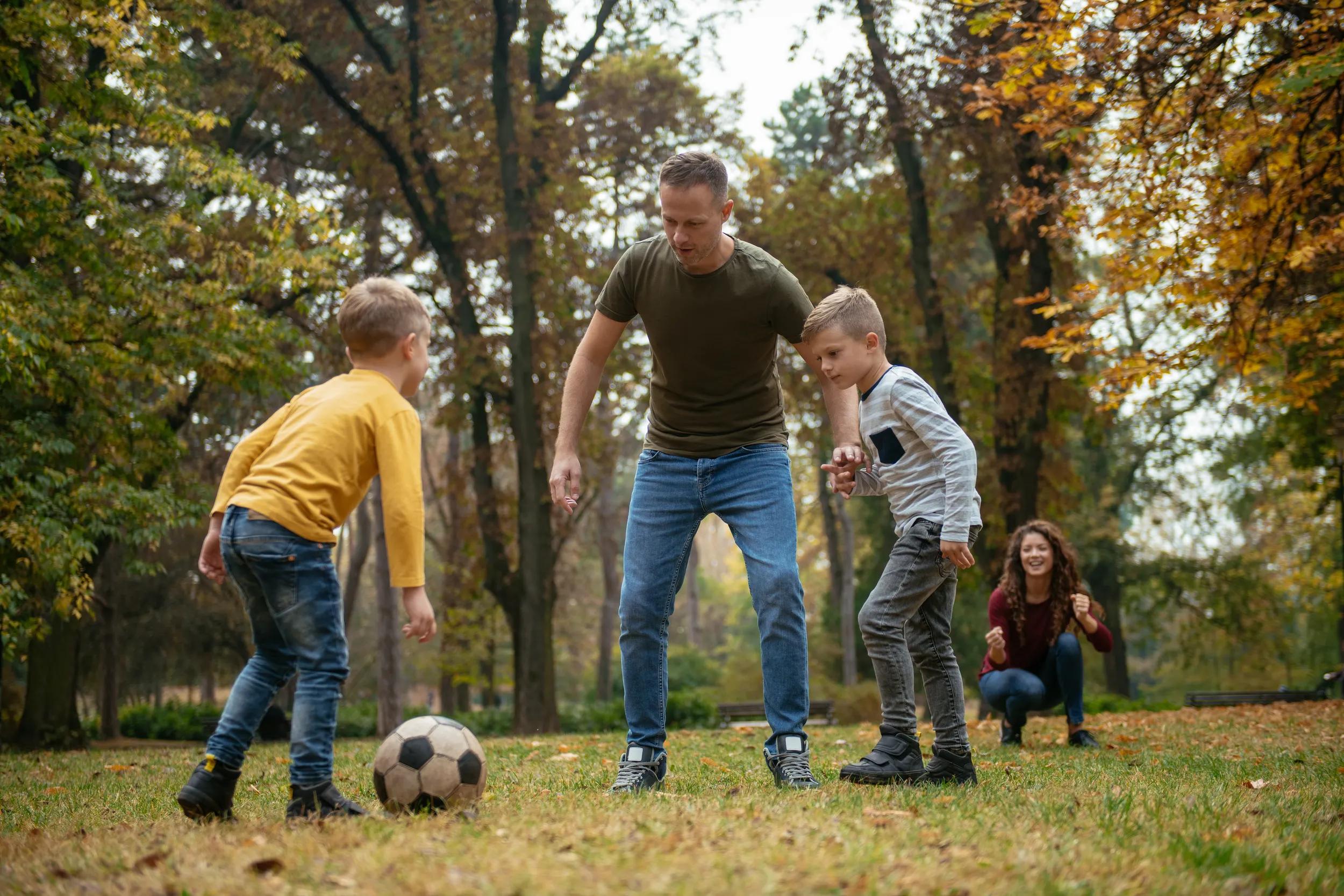 Father playing football with children in park
