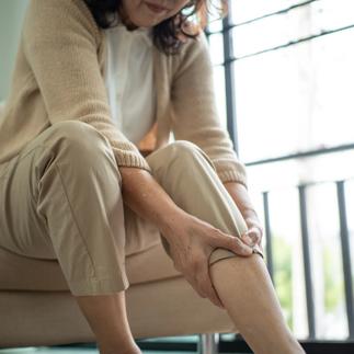 Elderly woman hand touching her suffering knee leg ankle joint pain showing arthritis symptoms with chronic pain and mobility problems aging health issues, insurance in retirement lifestyle