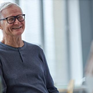 Smiling senior man laughing while chatting with friends in retirement home