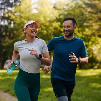Cheerful athletic couple jogging through the park.