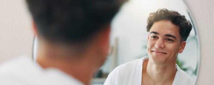 Happy man, mirror and check for cleaning in home with results, face reflection and grooming in morning. Beauty, facial glow and confident male person in house bathroom with smile, hygiene or skincare
