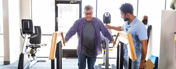 Mature male client uses the ramp to exercise during his physical therapy appointment