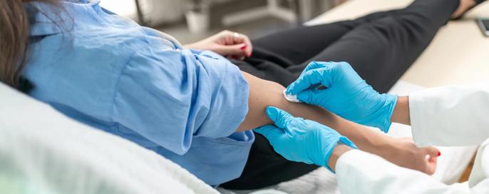 Healthcare worker drawing blood from a patient in a hospital room.