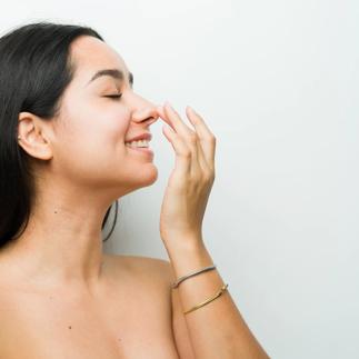Beautiful hispanic woman in a studio setting touches her nose after a rhinomodelation treatment, showing off her beauty