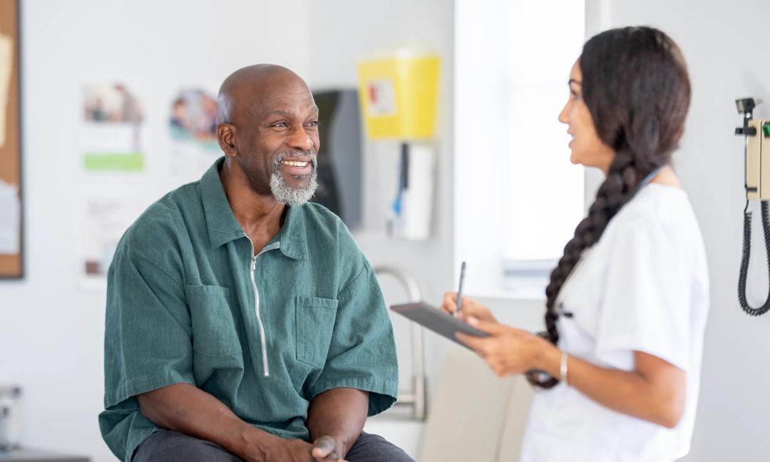 Friendly Black Man Patient Meets Female Clinician for Consultation in Modern Medical Clinic