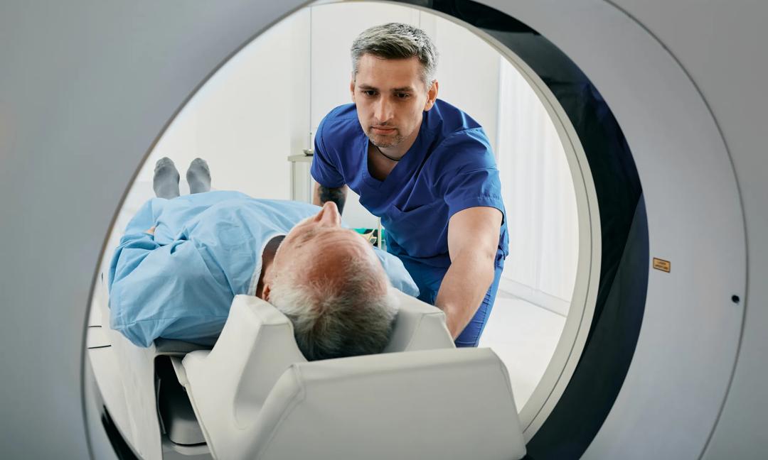Senior man going into CT scanner. CT scan technologist overlooking patient in Computed Tomography scanner during preparation for procedure