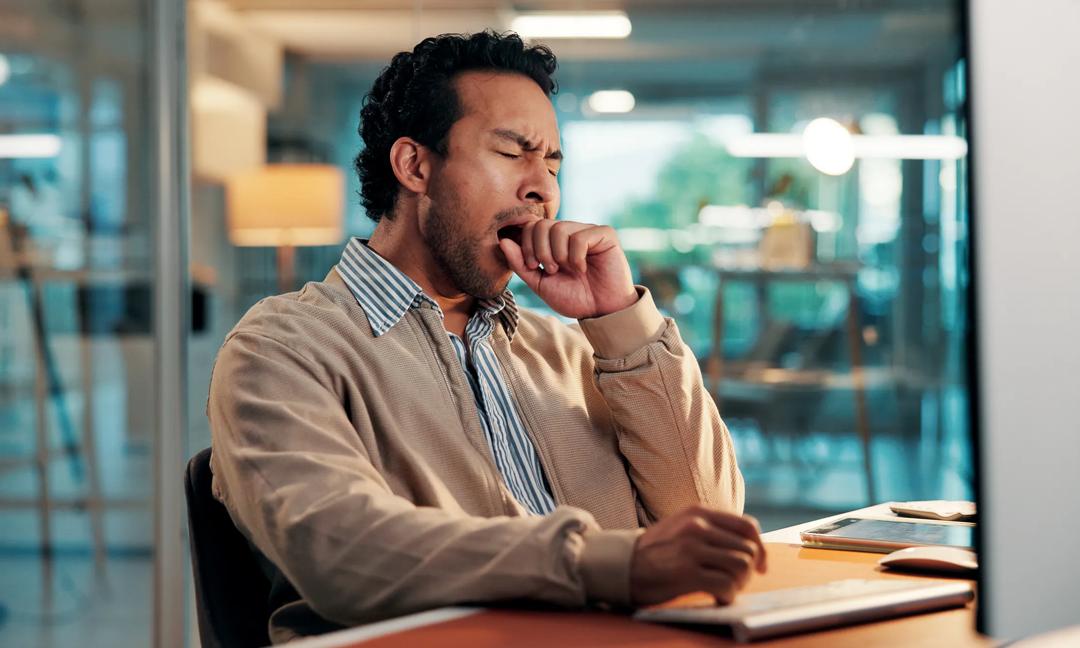 Tired, yawn and businessman in office with fatigue for creative project with online deadline. Burnout, overtime and male magazine editor with computer for publishing task with exhaustion in workplace