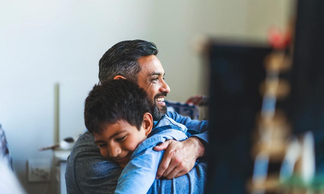 Smiling man embracing son in bedroom at home