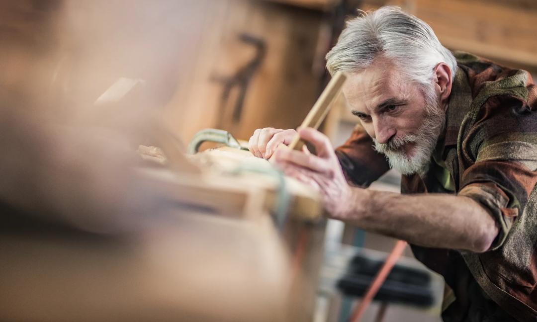 Expert carpenter inspecting  and measuring a piece of wood