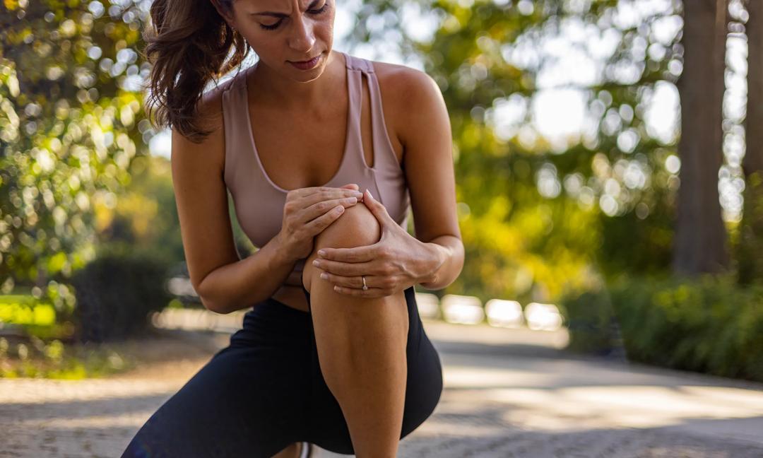 Young woman feeling pain in her knee.