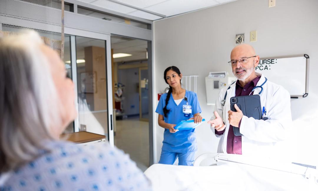 Mature Male Doctor and Hispanic Female Nurse visiting with a senior female patient and her husband