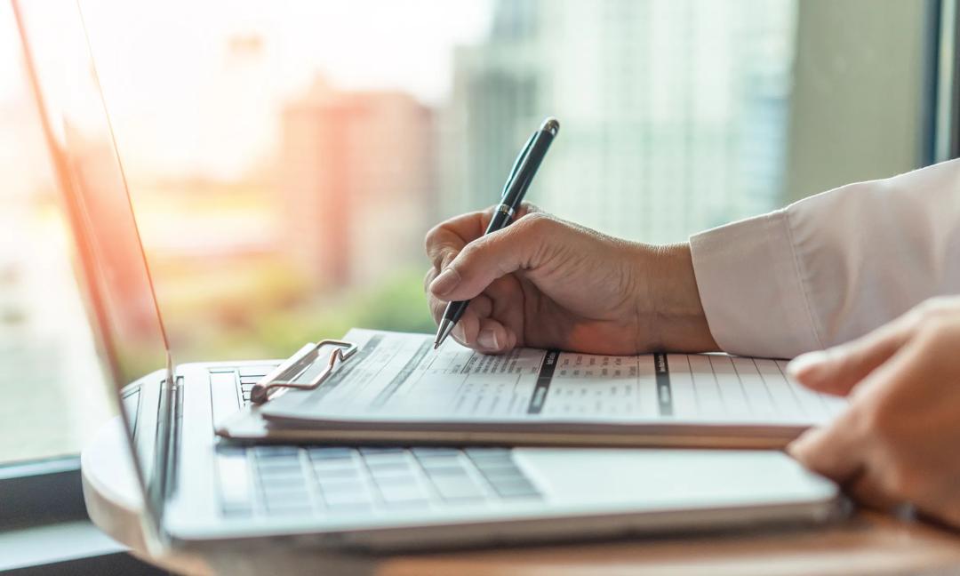 Administrator's hand fill in business schedule form document writing on yearly work plan, monthly timetable sheet, or weekly time table paper for office tasks, things and jobs to do list