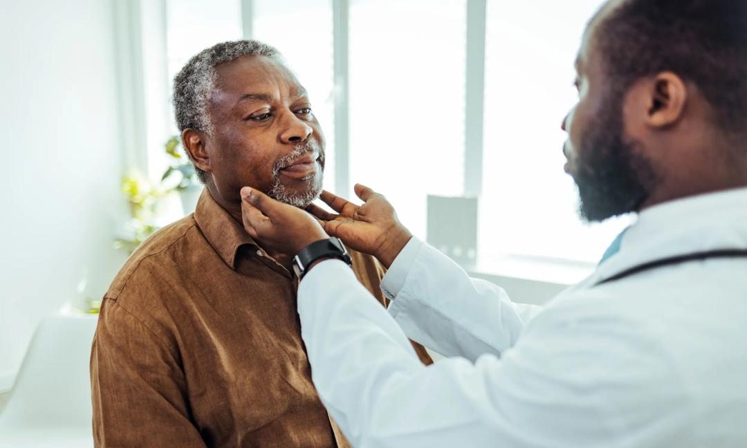 Doctor doing throat examination on older man