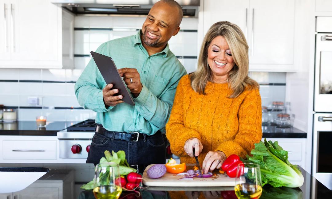 Mixed race couple cooking together in modern kitchen.