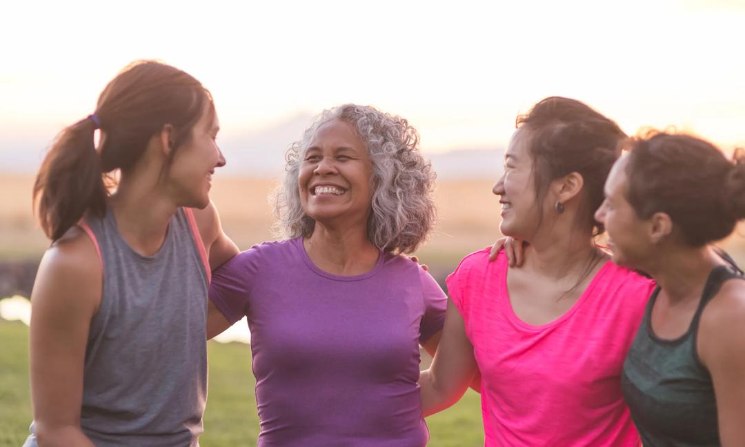 Four ethnic women laughing together after an outdoor workout