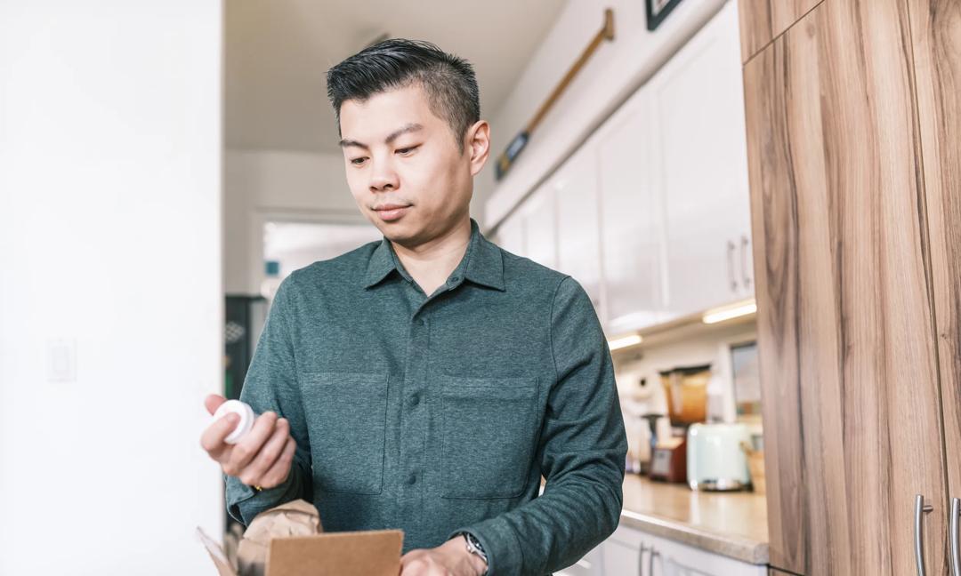 Young Asian man unpacking medicine delivery at home
