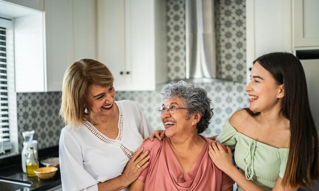 Three generation family embracing and talking in the kitchen at home