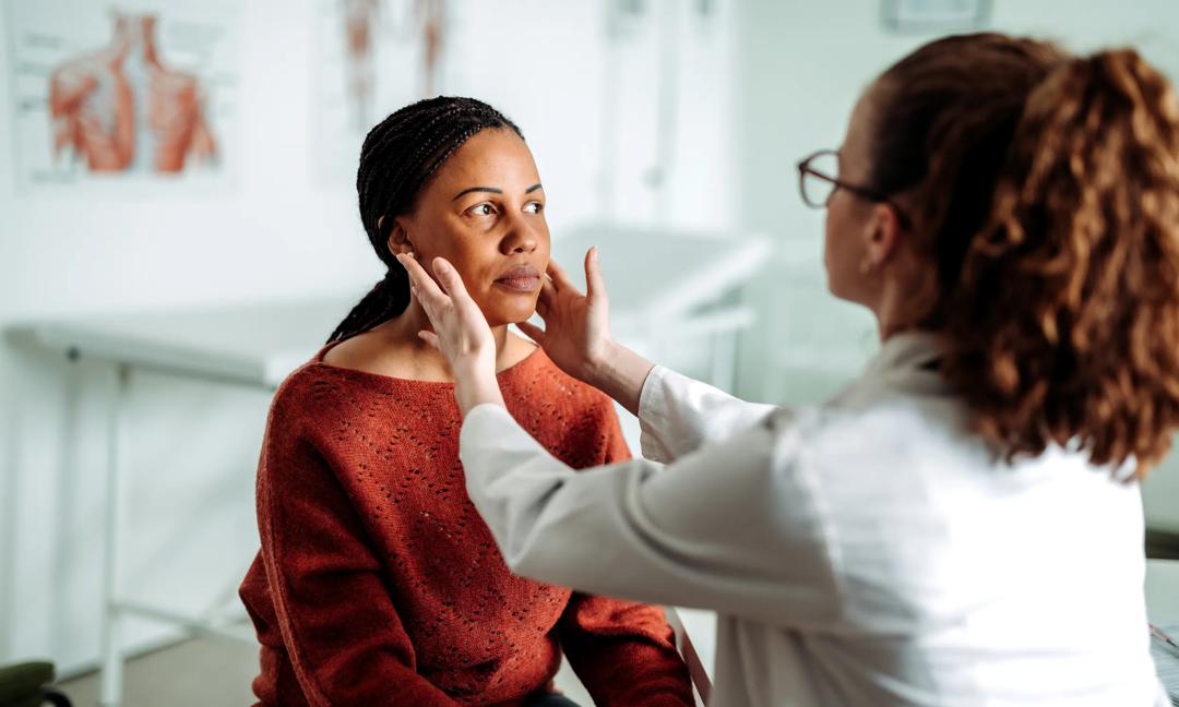 Female doctor examining lymph nodes on female patient at the office
