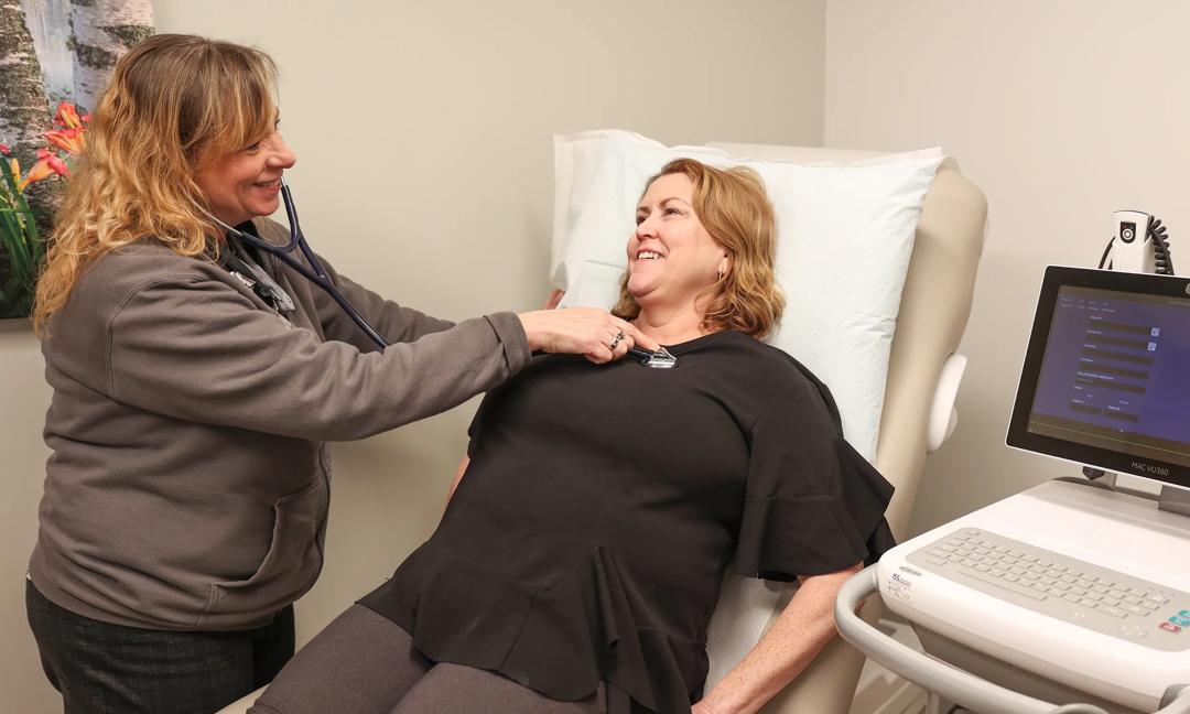 Nurse checking patients heart rate heart beat using a stethoscope