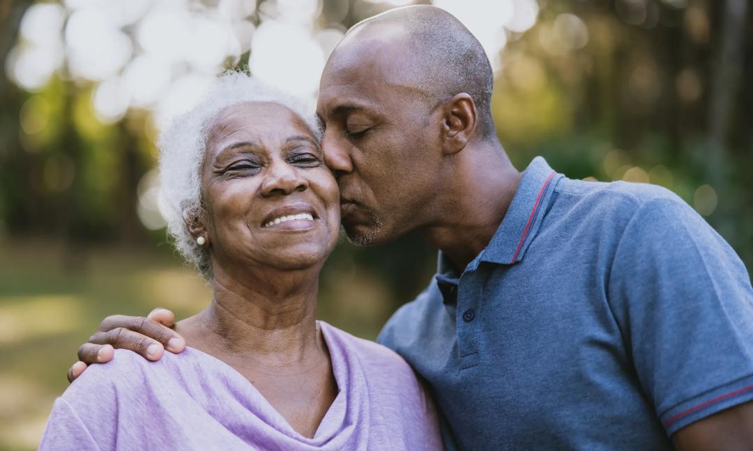 Portrait of an elderly mother and adult son kiss on cheek