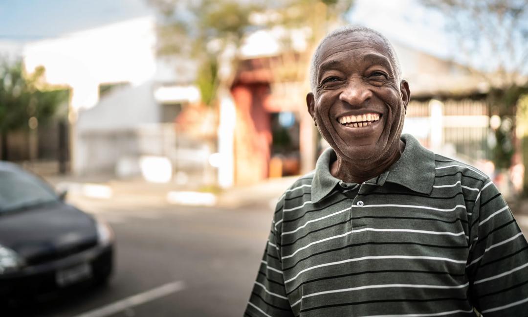 Portrait of smiling afro senior man looking at camera on the street