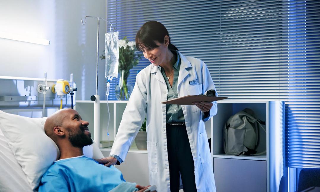 Doctor, clipboard and man in hospital bed, conversation and feedback for diagnosis. Medical service, patient and professional in clinic, healthcare and documents for test results, healing or recovery