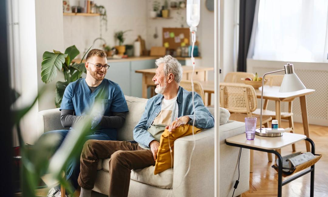 Male caregiver talking with a senior patient at home