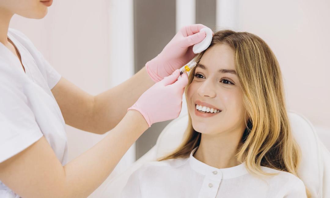Professional beautician performing botox injection on smiling woman's forehead, rejuvenating facial features in sleek clinic setting