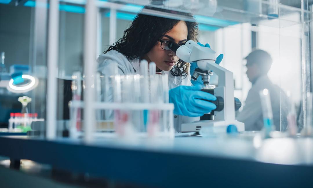 Medical Science Laboratory: Portrait of Beautiful Black Scientist Looking Under Microscope Does Analysis of Test Sample. Ambitious Young Biotechnology Specialist, working with Advanced Equipment