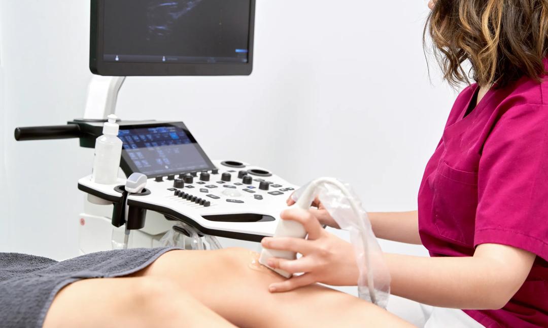 Doctor conducting ultrasound examination of patient's knee in clinic