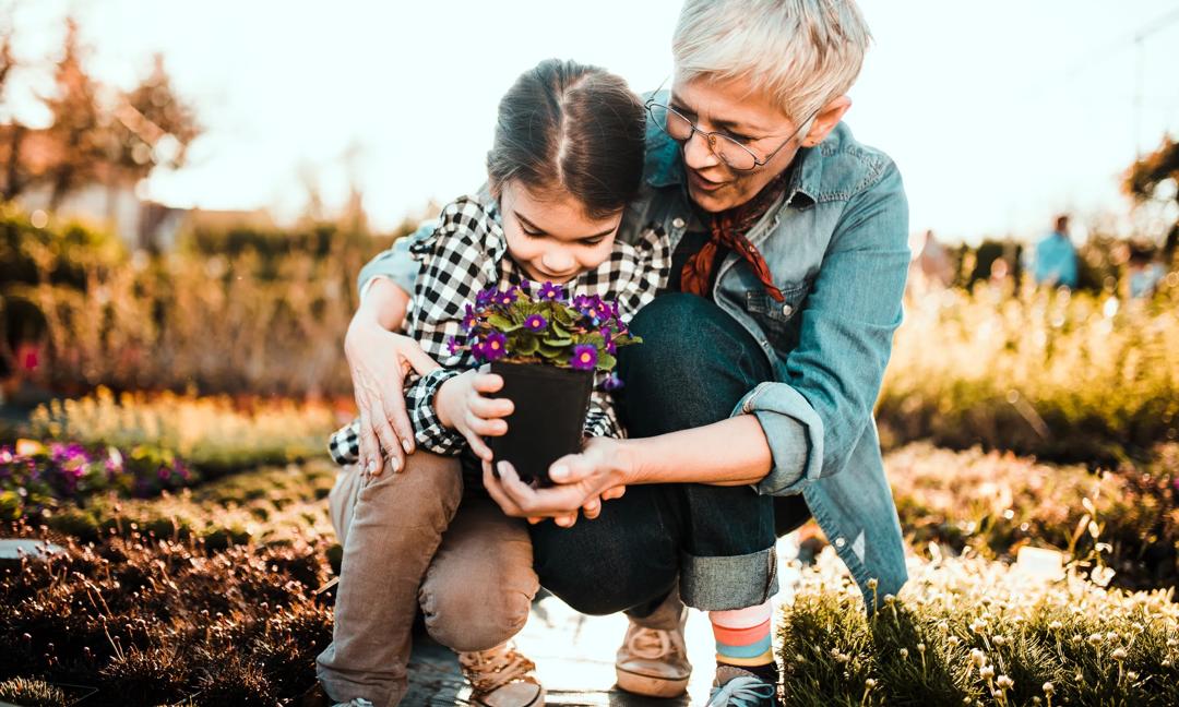 Woman helping granddaughter holding the flowers
