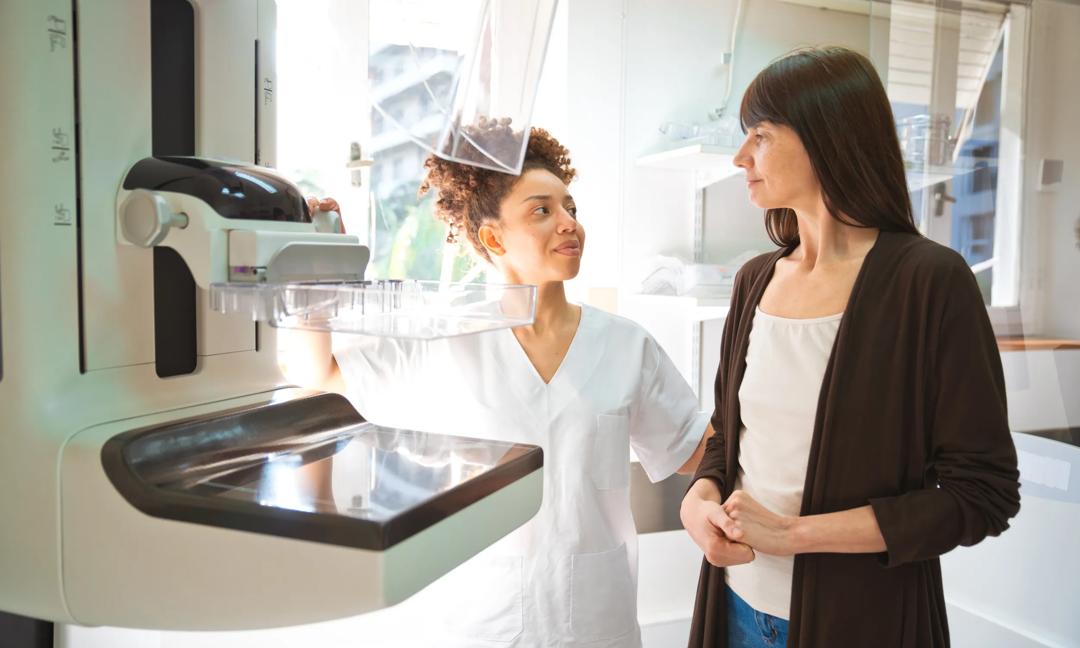 Female doctor talking to patient during Mammography test in examination room
