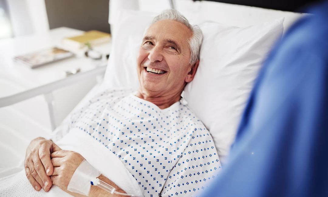Shot of a senior man talking to his carer while lying in his hospital bed