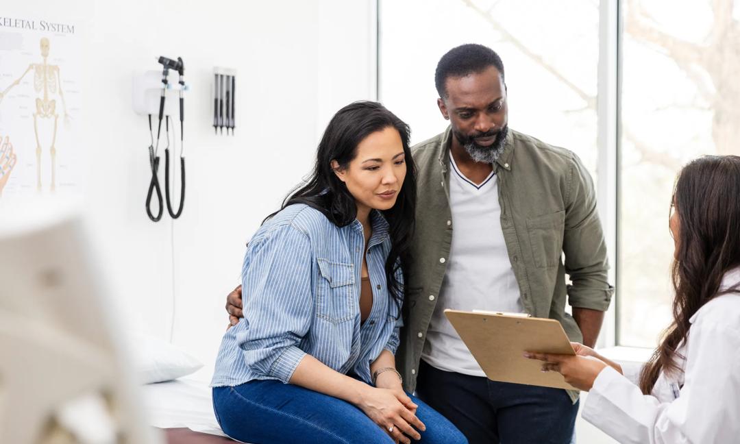 Couple discussing healthcare with a doctor in a medical clinic