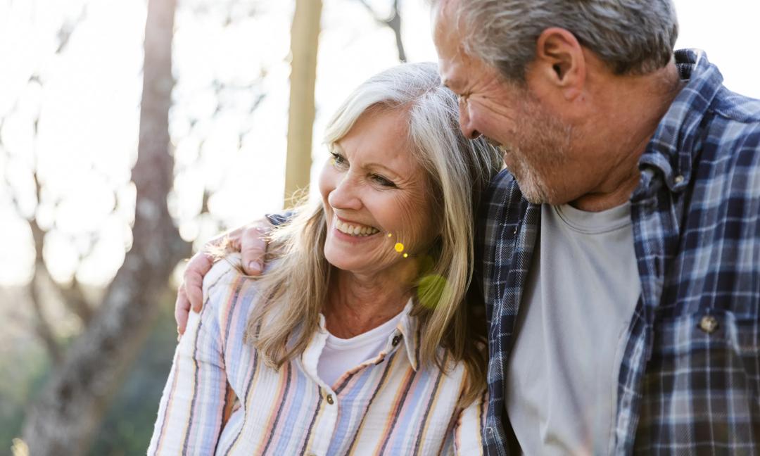 Senior man puts arm around happy senior wife