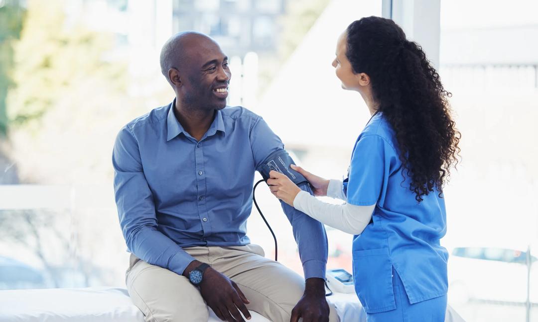 Doctor woman, patient and blood pressure consultation in hospital for healthcare or health insurance. Black man and professional nurse talking about hypertension, wellness and advice for healthy life