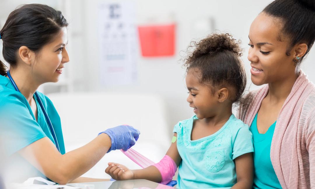 Female phlebotomist wraps young girl's arm after blood draw