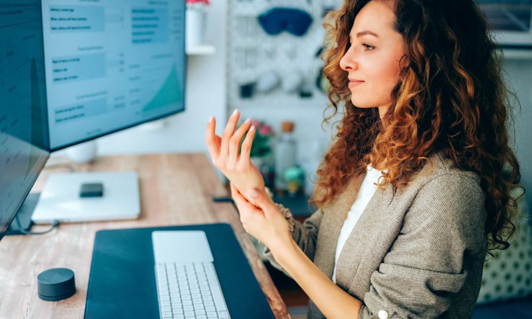 Businesswoman using hand cream while working at standing desk in modern home office