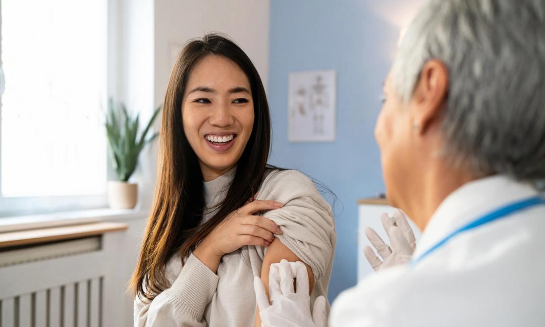 Senior Caucasian female doctor, giving an flu vaccine to a female patient Japanese ethnicity, during an annual medical check-up