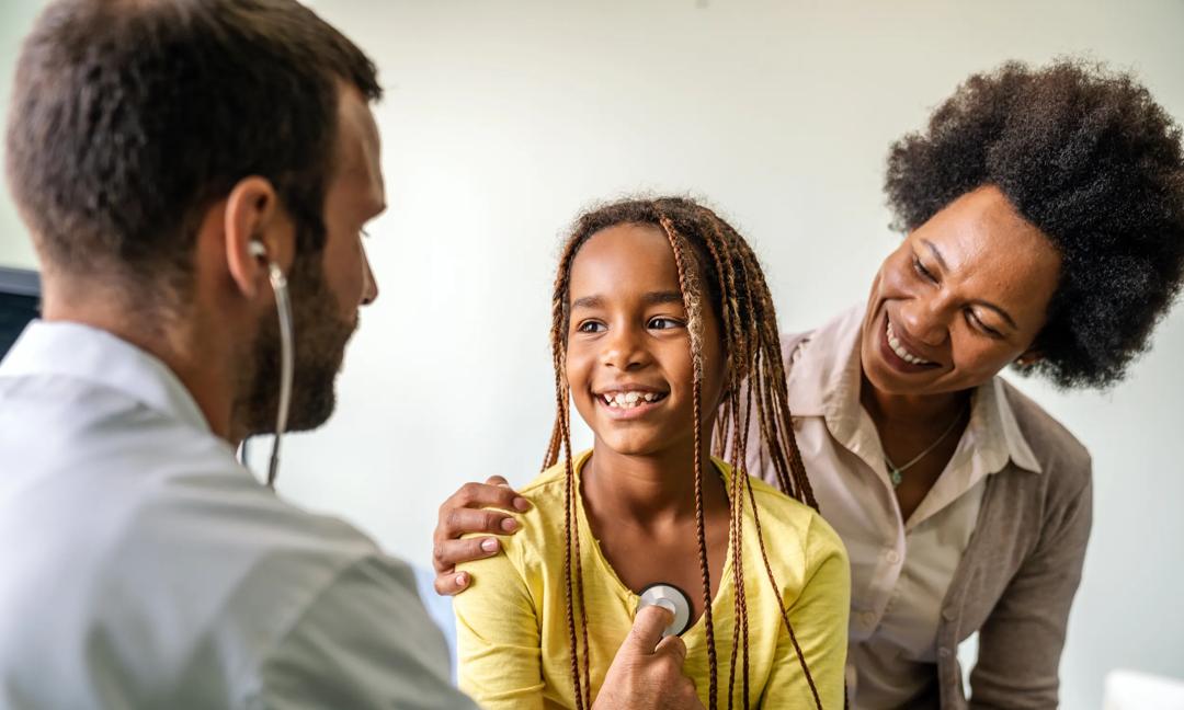 Pediatrician examining a little african girl at hospital. Healthcare, people concept