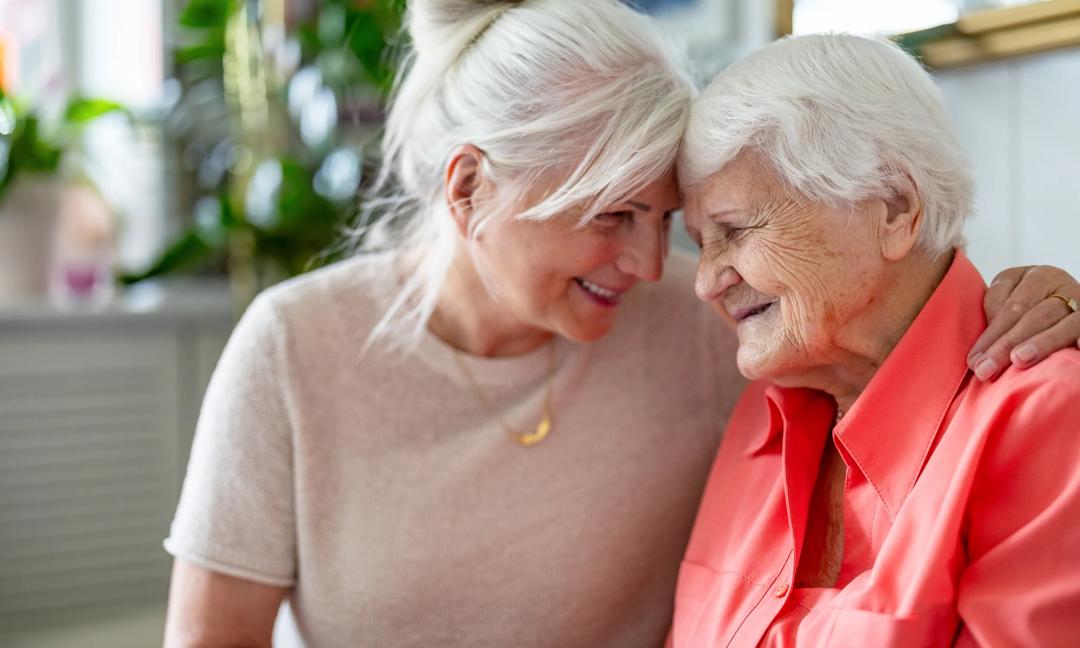 Happy senior woman with her adult daughter at home