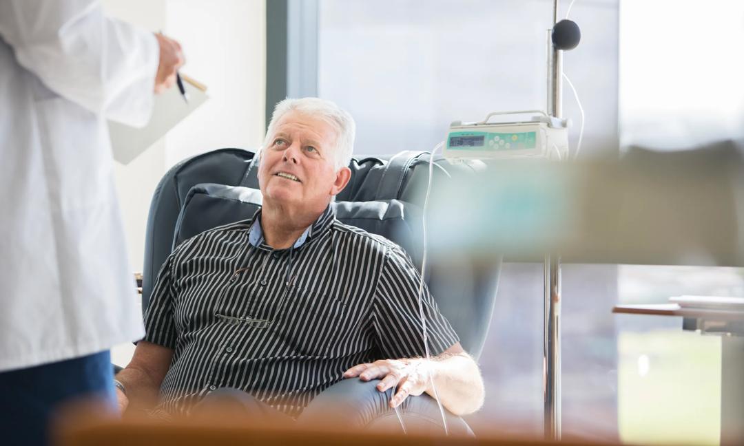 Doctor talking to patient receiving medical treatment in hospital ward