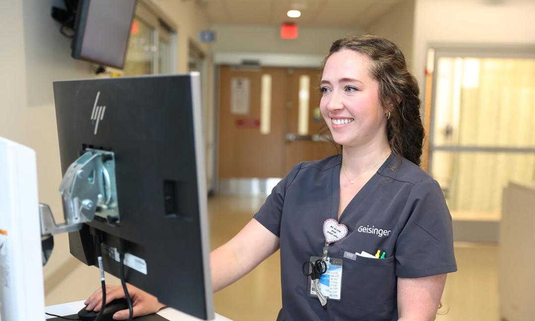 Kaitlyn Snyder Nurse posing at nursing station in hallway