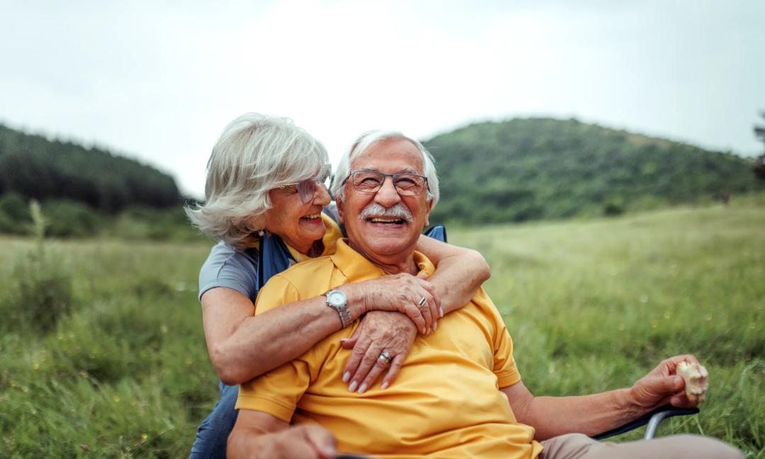 Affectionate senior couple bonding while camping together at forest