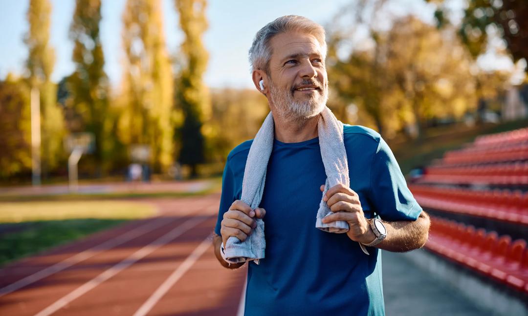 Portrait of smiling mature athlete at the stadium looking away.